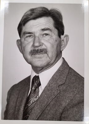 A black and white portrait of a man with a moustache.